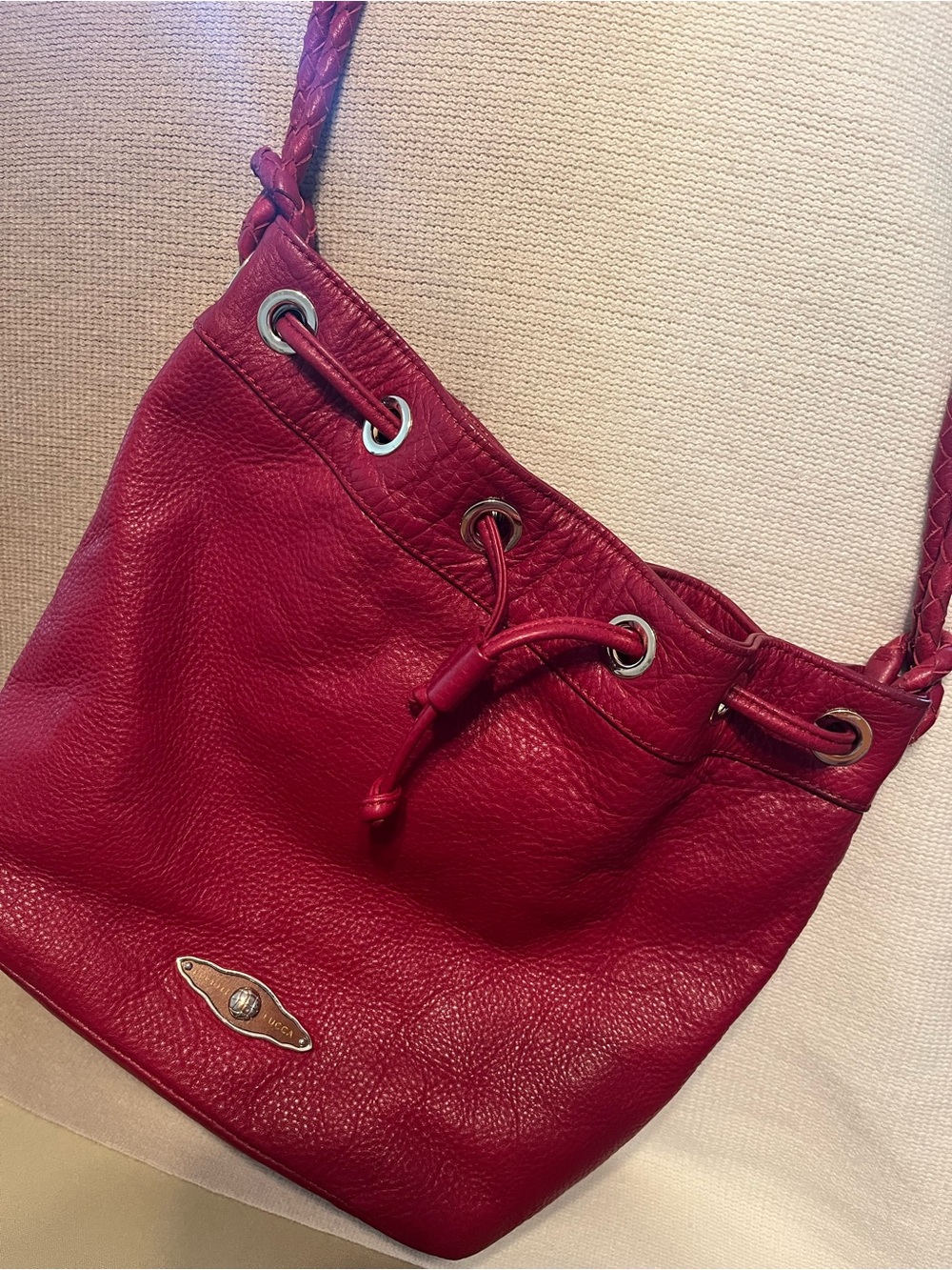 Elliott Lucca Red Pebbled Leather Bucket Bag. Braided handles. Tassel closure